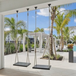 a courtyard with palm trees and swings