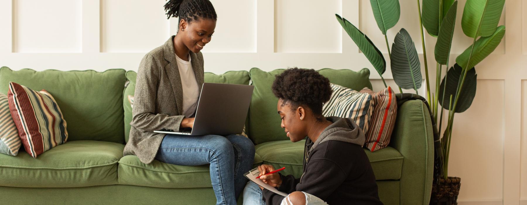 a man and a woman sitting on the floor looking at a laptop