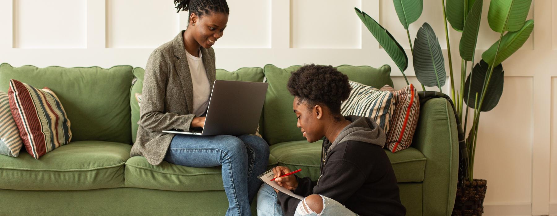 a man and a woman sitting on the floor looking at a laptop